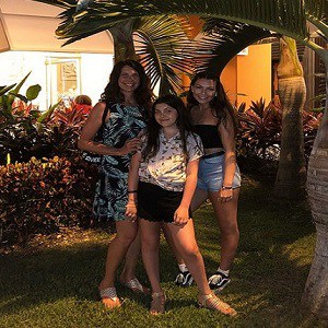 Brightly lit garden with three women enjoying outdoor space in a tropical setting.