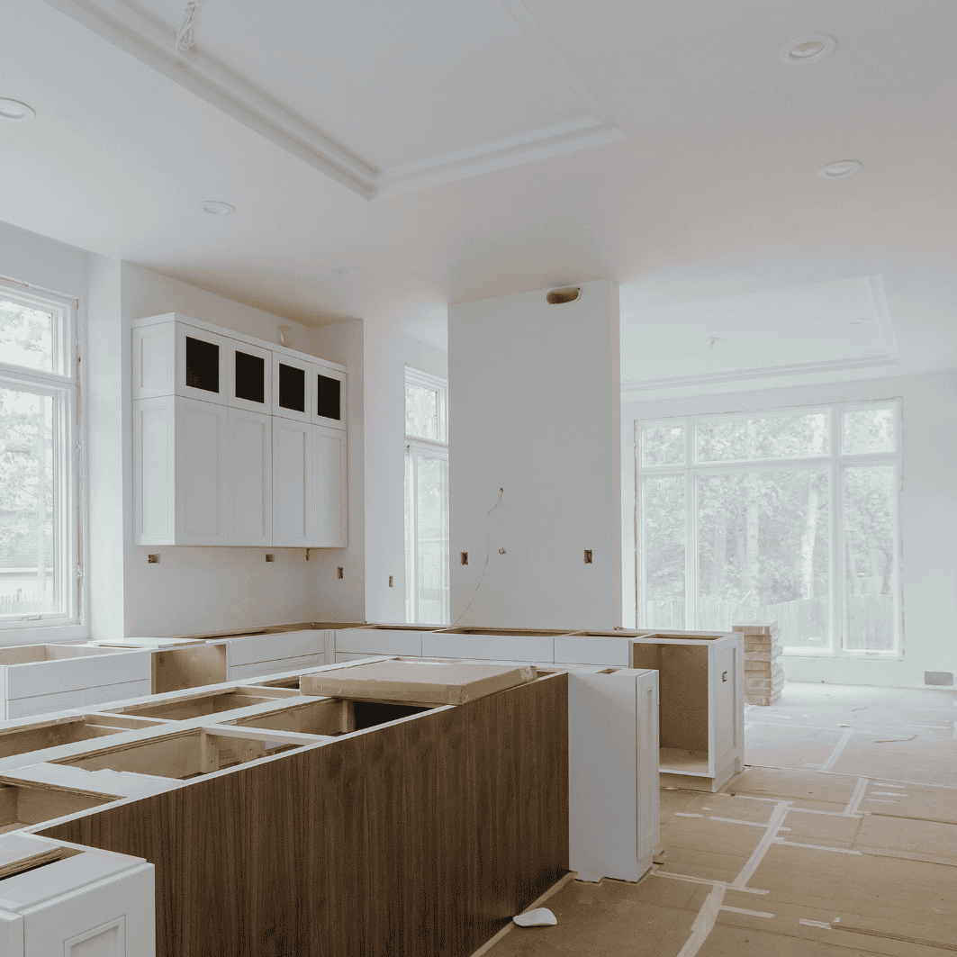 Kitchen under renovation with cabinets and large windows.
